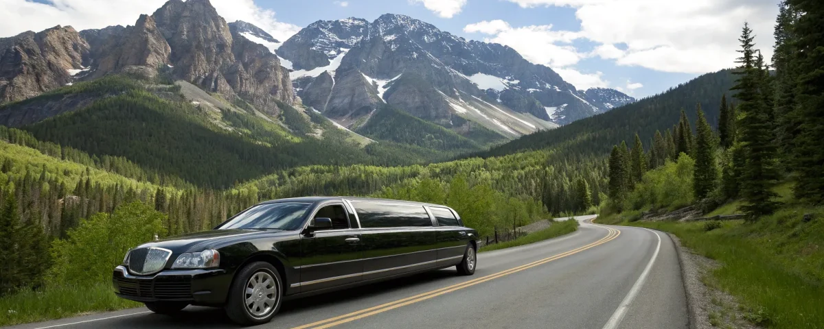 Black limousine on a scenic mountain road offering transportation services in Denver, CO.
