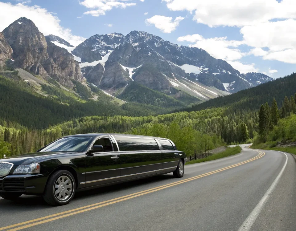 Black limousine on a scenic mountain road offering transportation services in Denver, CO.