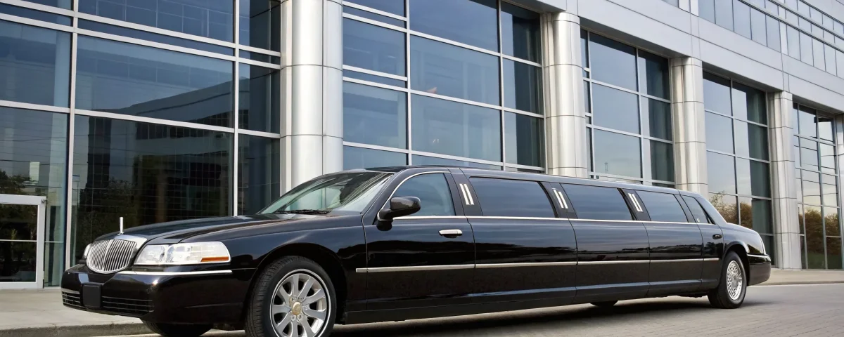 A professional Loveland limo service with a black stretch limousine parked by a modern building.