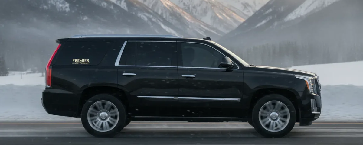 Luxury black Cadillac Escalade driving on snow-covered I-70 mountain highway near Vail Colorado